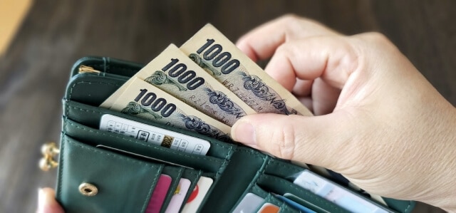 財布から3,000円を出す女性の手